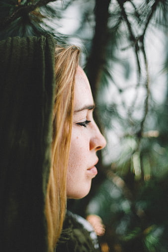 Serene woman in forest with eyes closed