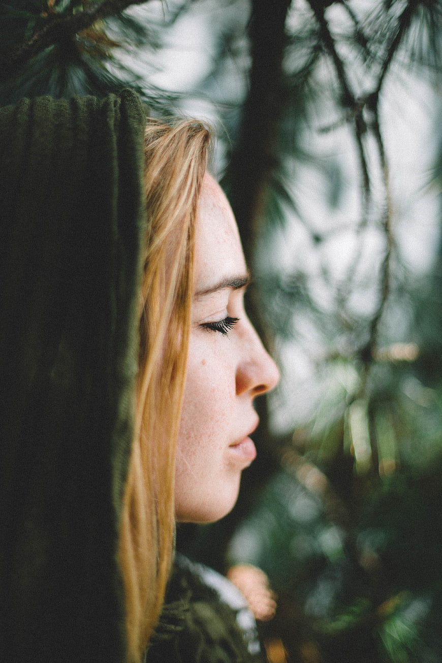 Serene woman in forest with eyes closed