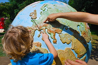 Child and Adult Pointing at Large Outdoor Globe Map