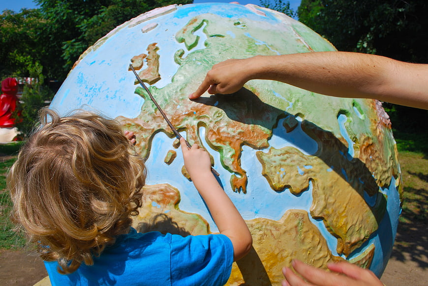 Child and Adult Pointing at Large Outdoor Globe Map