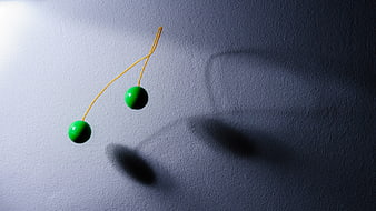 Green balls on string casting shadows on textured wall