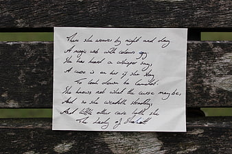 Handwritten Poem on White Paper Resting on Weathered Wooden Bench