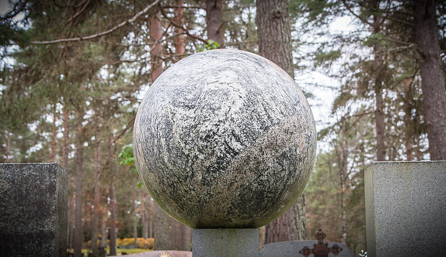 Granite sphere monument in a forest cemetery setting