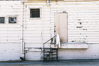 Weathered white building exterior with metal stairs and hanging jacket