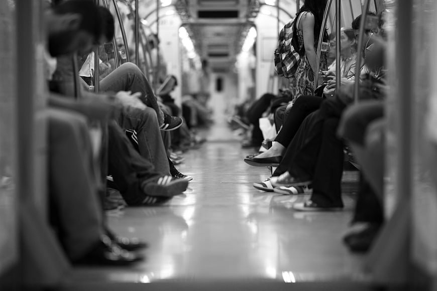 Black and white subway commuters sitting in train car