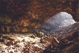 Sunlight streaming through rocky cave entrance with rugged interior
