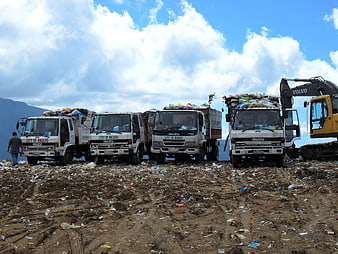 Garbage trucks at landfill site with excavator
