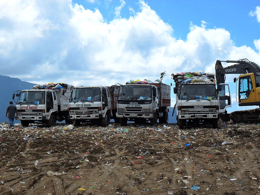 Garbage trucks at landfill site with excavator