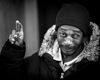 Black and white portrait of a man in a winter coat pointing upward