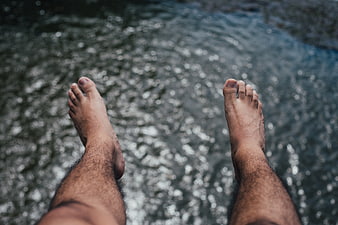 Relaxed bare feet dangling over shimmering river water