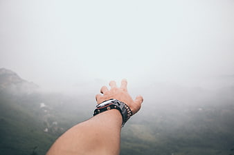 Hand Reaching Out Over Foggy Mountain Landscape