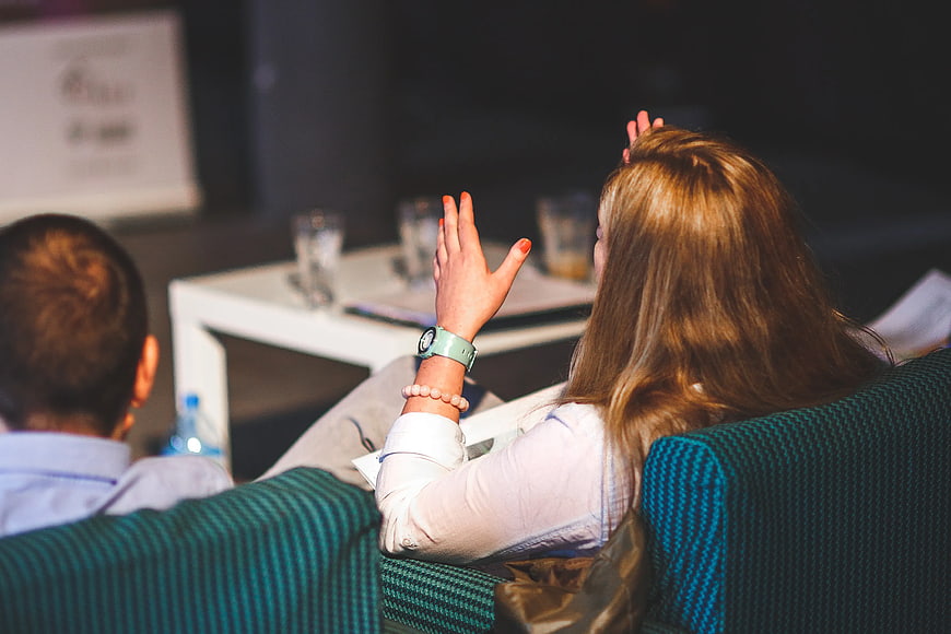 Woman raising hand at business conference presentation
