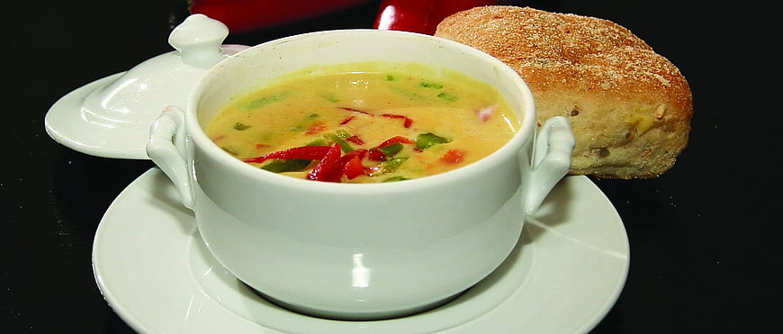 Creamy yellow curry soup with bread in white bowl