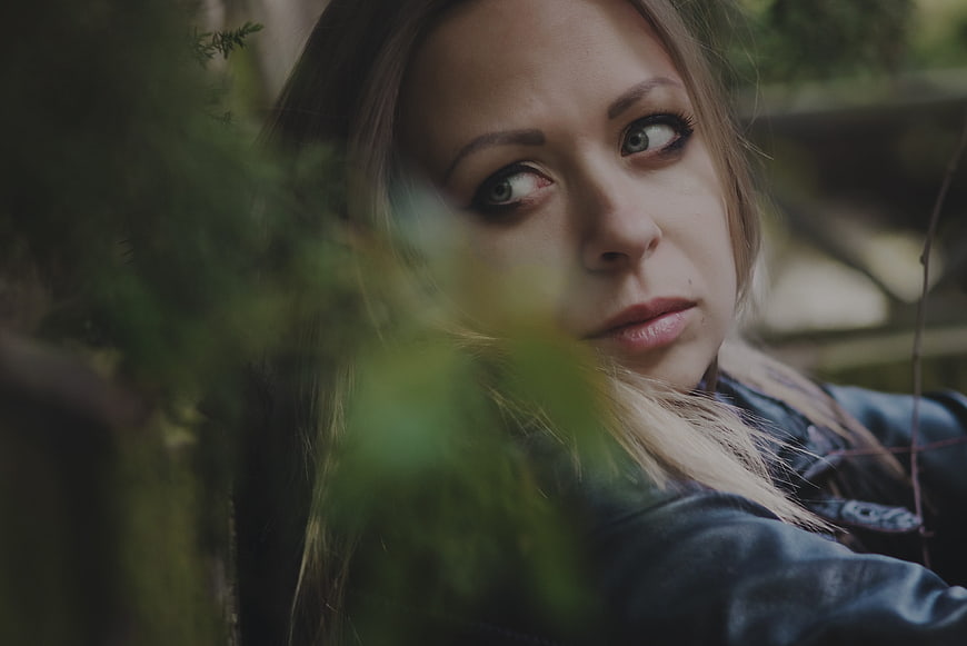 Cinematic portrait of a woman looking sideways through foliage