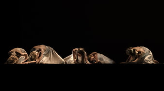 Group of female dancers in white on black stage