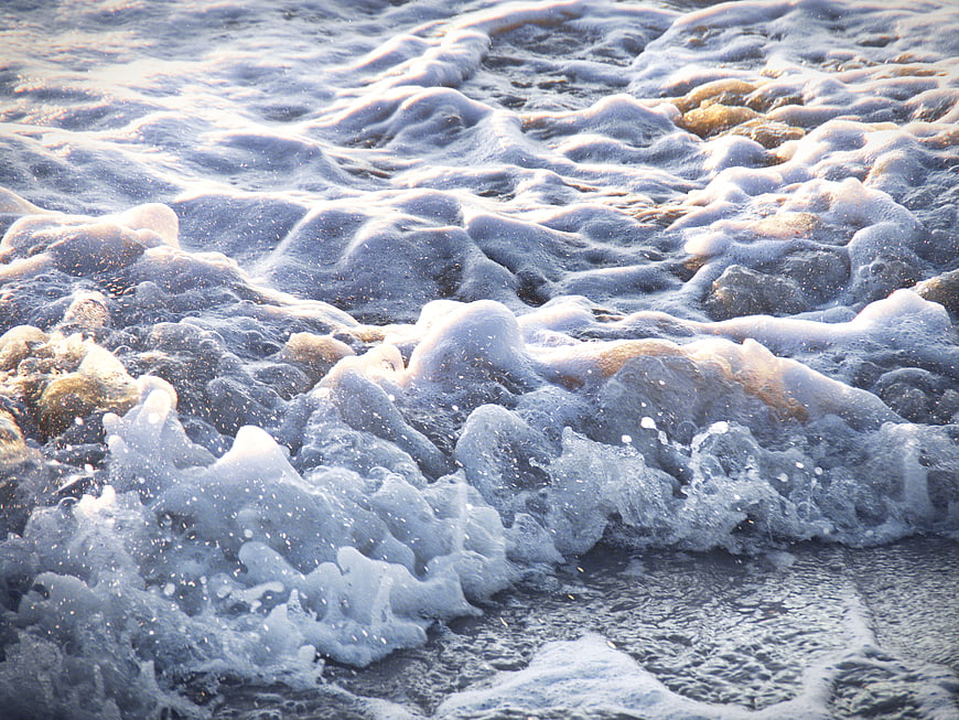 Close-up of foamy ocean waves crashing on sandy shore