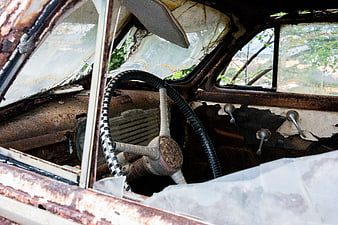 Rusty vintage car interior with broken windshield and steering wheel