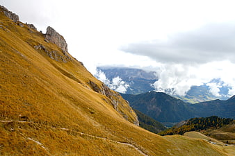 Golden Autumn Mountain Slope with Cloudy Peaks