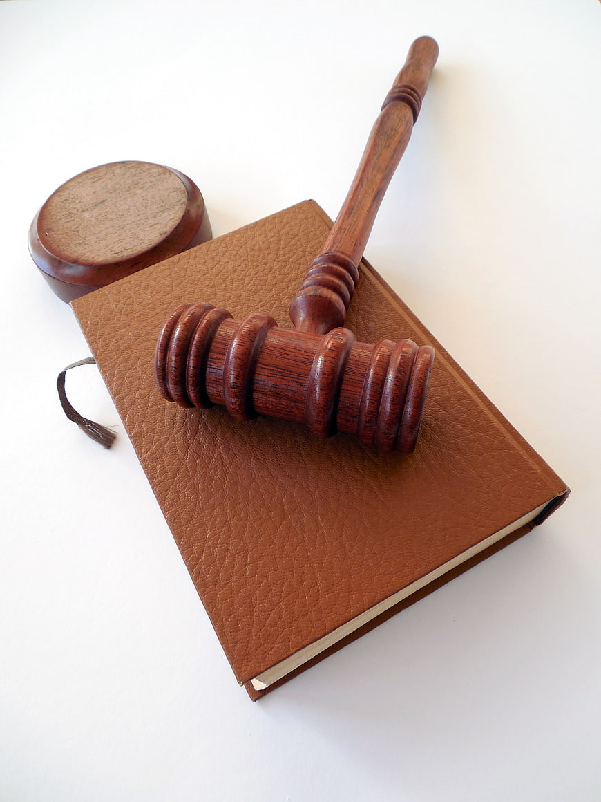 Wooden judge gavel and sound block on brown leather law book