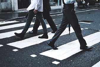 Men walking across city crosswalk on wet street