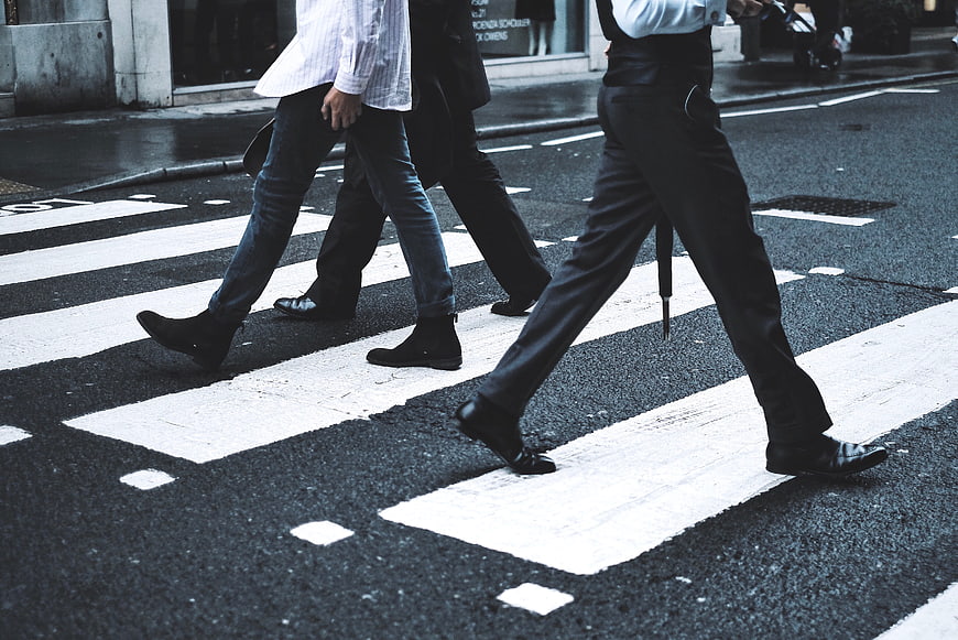 Men walking across city crosswalk on wet street