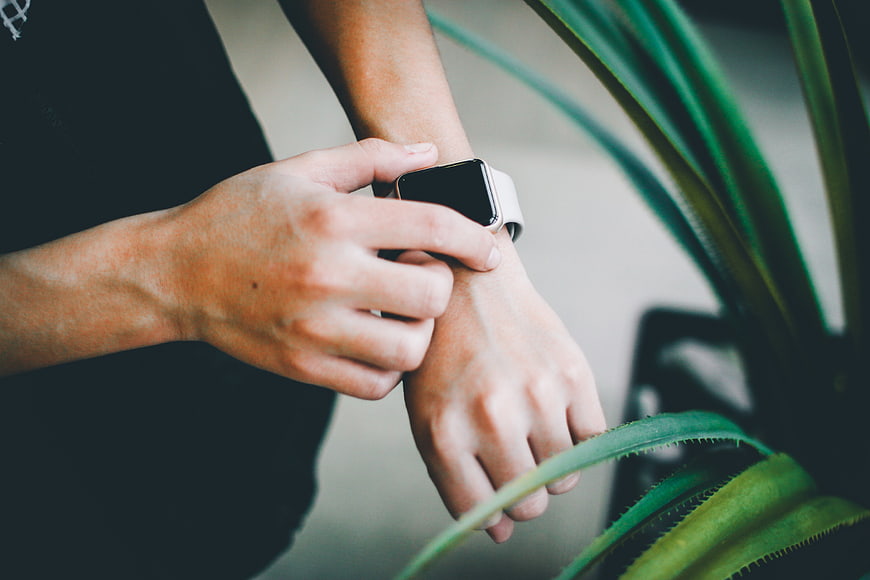 Man Checking Smartwatch on Wrist Near Plant