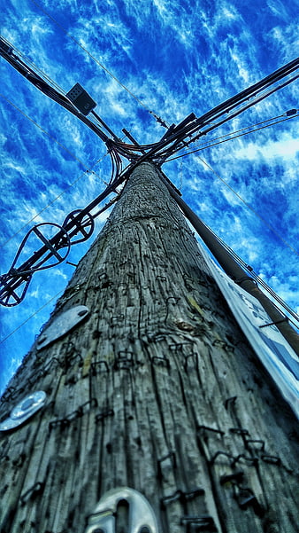Low angle view of wooden utility pole against blue sky