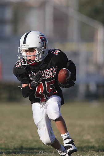 Young Football Player Running with Ball on Field