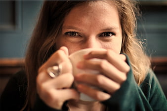Close-up of woman drinking coffee with intense eye contact