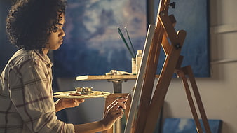 Young woman painting on canvas in art studio