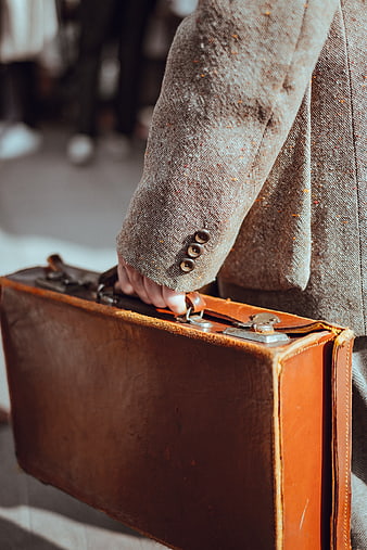 Vintage brown leather briefcase held by man in tweed jacket