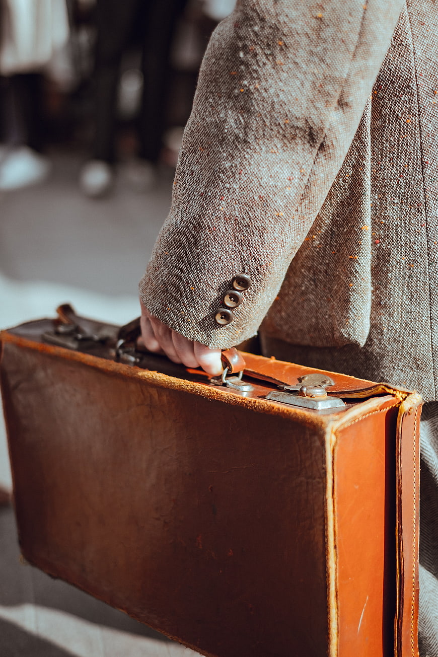 Vintage brown leather briefcase held by man in tweed jacket
