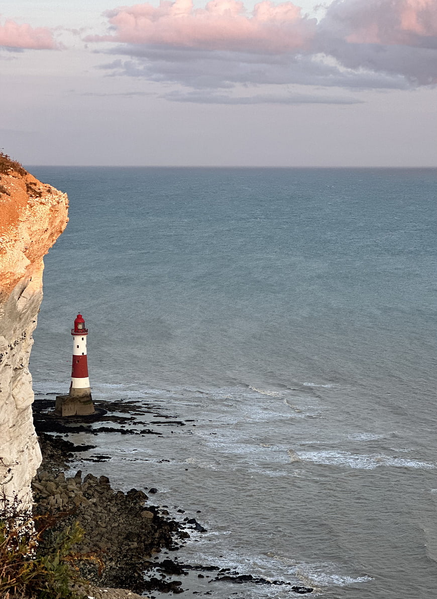 Red and White Lighthouse on Coastal Cliff at Sunset