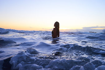 Woman in Ocean Waves at Sunset