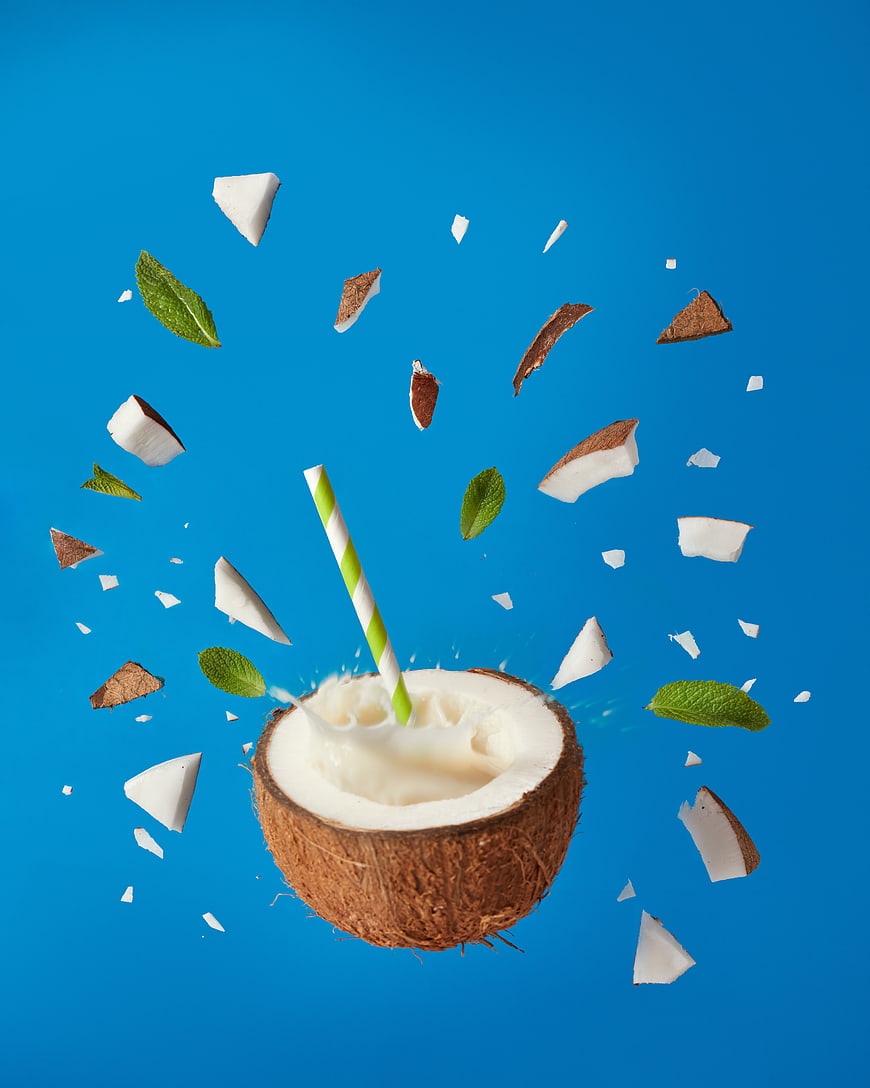 Fresh Coconut Water with Mint and Floating Chunks on Blue Background