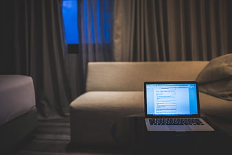 Laptop on table in dimly lit hotel room at night