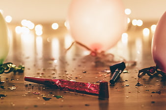 Party aftermath with balloons, confetti, and party poppers on wooden table