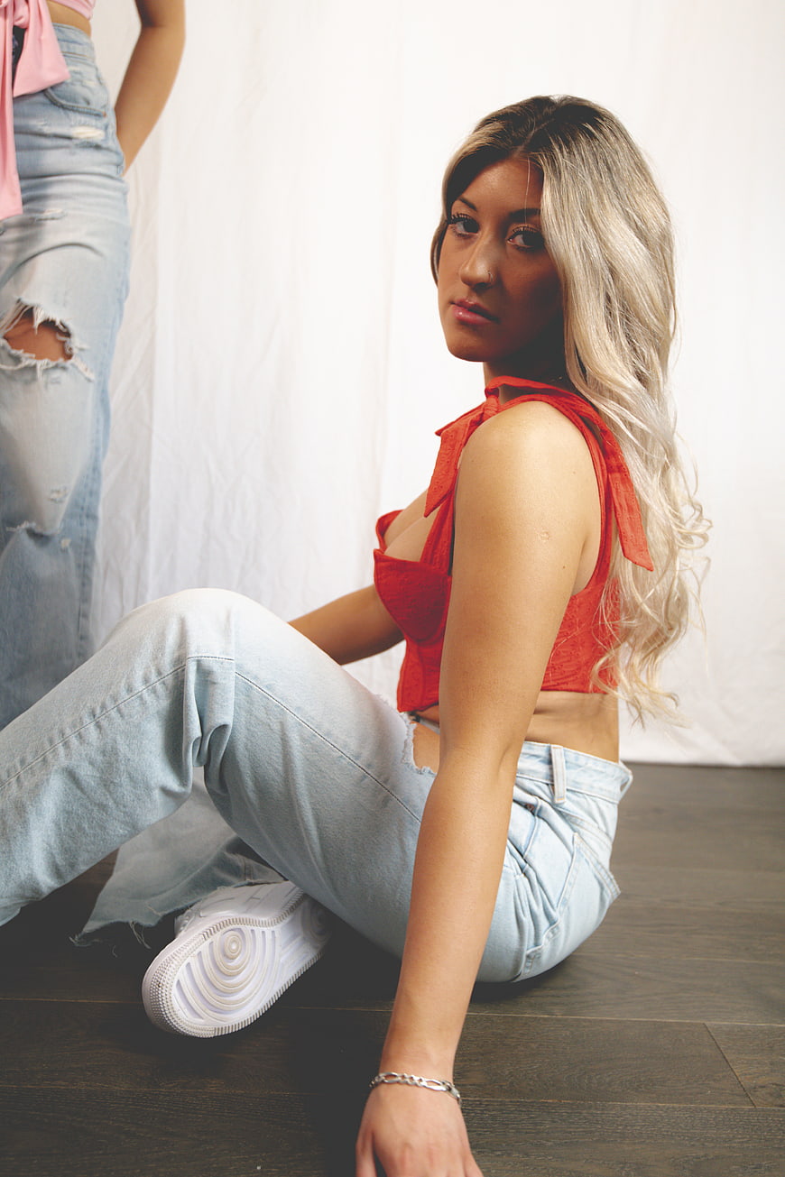 Blonde Woman in Red Top and Jeans Sitting on Floor