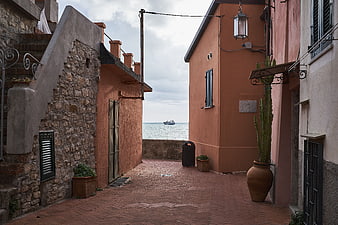 Narrow Mediterranean alleyway with terracotta buildings and sea view