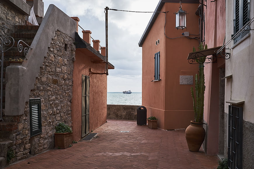 Narrow Mediterranean alleyway with terracotta buildings and sea view