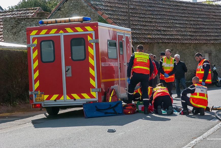 Emergency Medical Team Treating Patient On Roadside Near Fire Truck