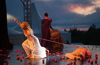 Dramatic outdoor ballet performance at sunset with red apples