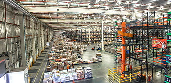 Interior of a large logistics distribution center with stacked boxes and racking