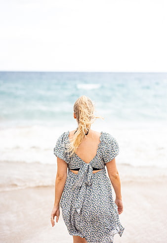 Woman in Floral Dress Walking on Beach Toward Ocean