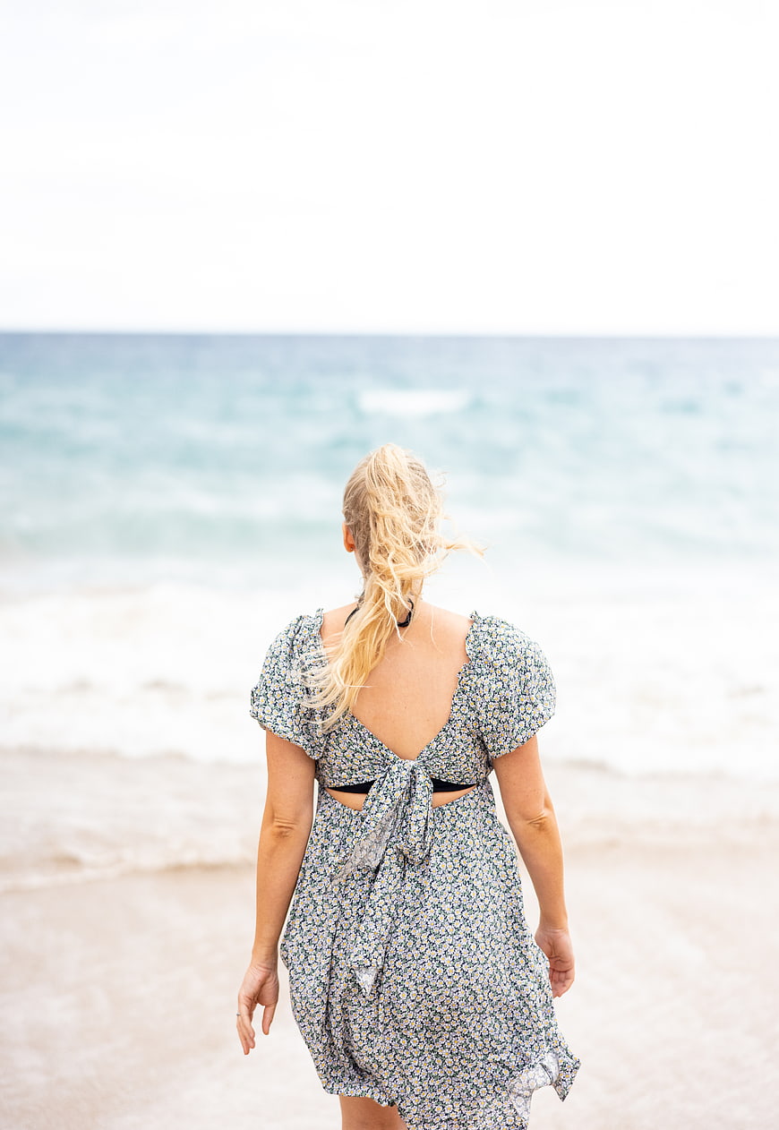 Woman in Floral Dress Walking on Beach Toward Ocean