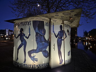 Illuminated Public Urinal with Artistic Murals at Night