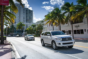 White SUV driving on sunny Miami Beach street with palm trees