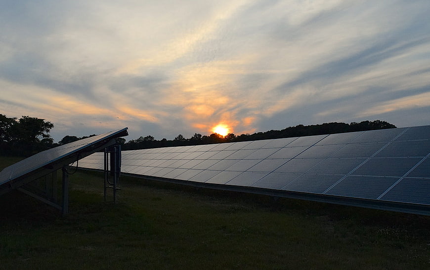 Solar Panels in Field at Sunset with Cloudy Sky