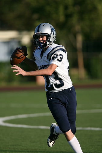 Football Player Catching Ball on Green Field