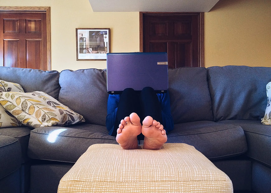 Person relaxing on couch with laptop and bare feet